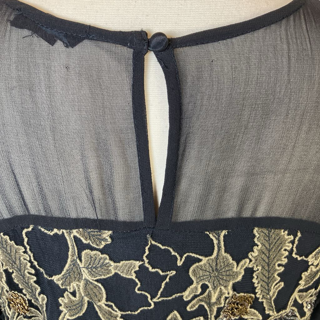 Gray garment with floral embroidery on a beige background