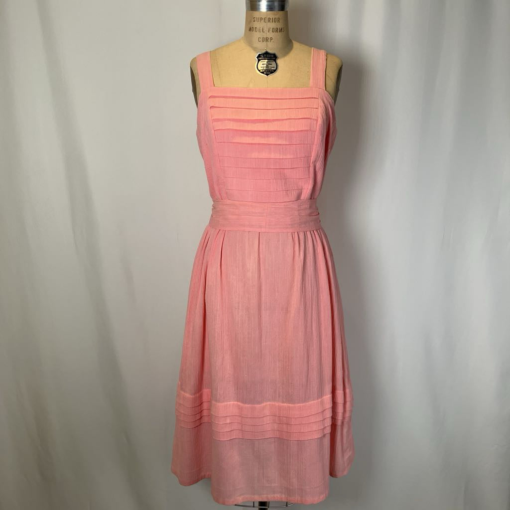 Pink dress on a mannequin against a plain background