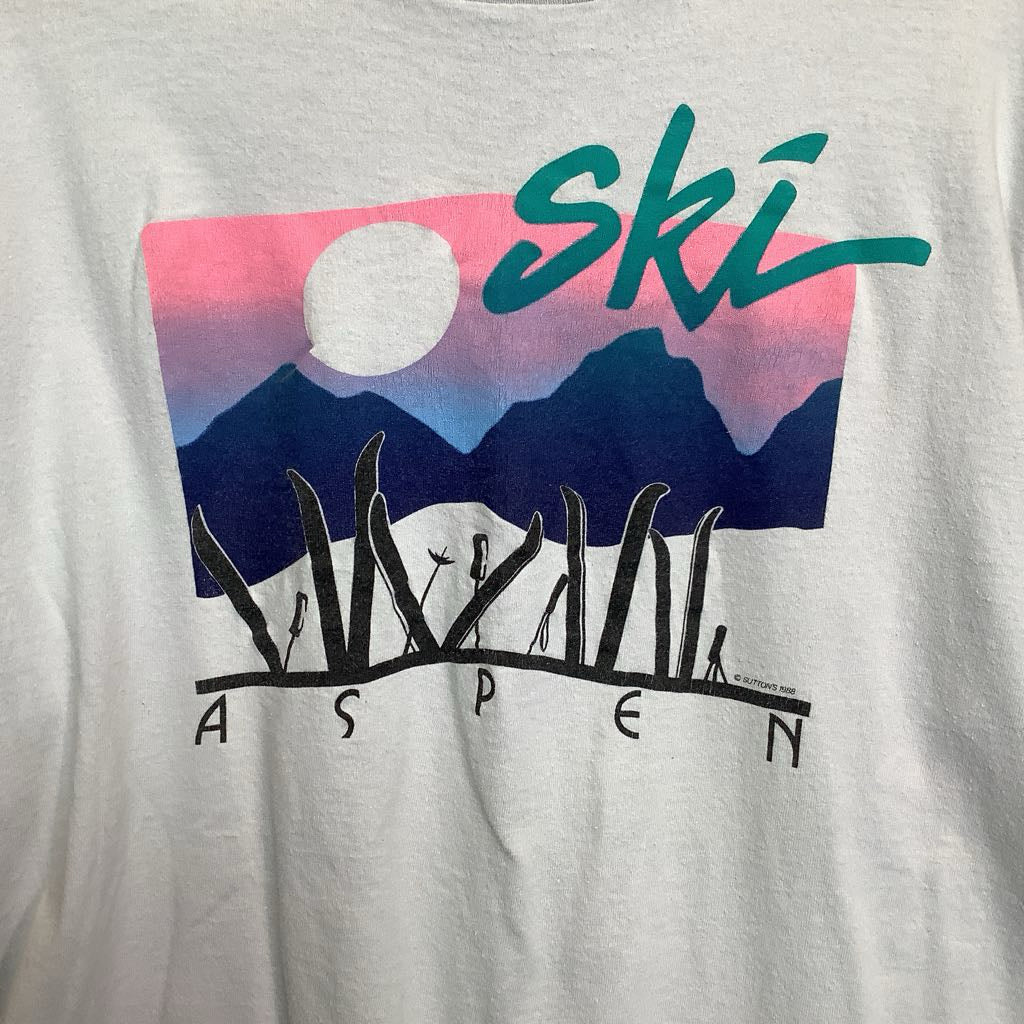 Gray t-shirt with a graphic of mountains, sun, and 'Ski Aspen' text on a white background