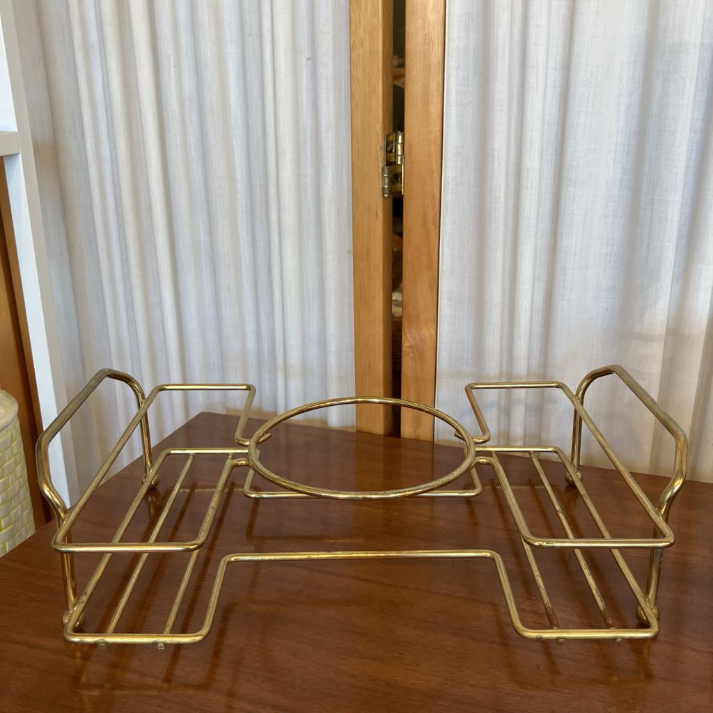 Gold metal tray on a wooden surface with a fabric screen background 