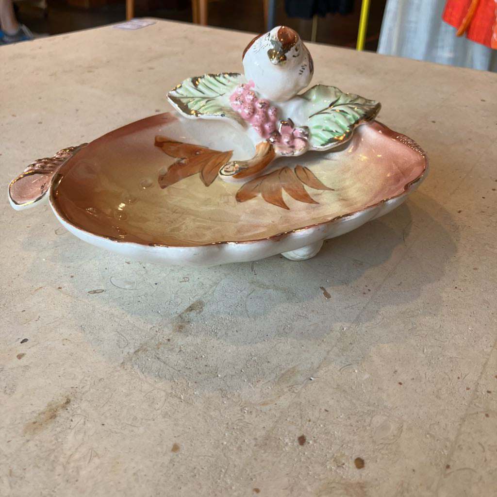 Decorative ceramic dish with a bird and floral design on a shell shaped base