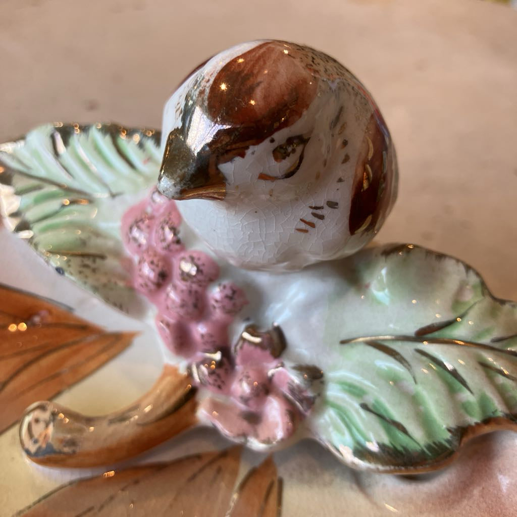 Decorative ceramic piece of a bird with flowers on a leaf