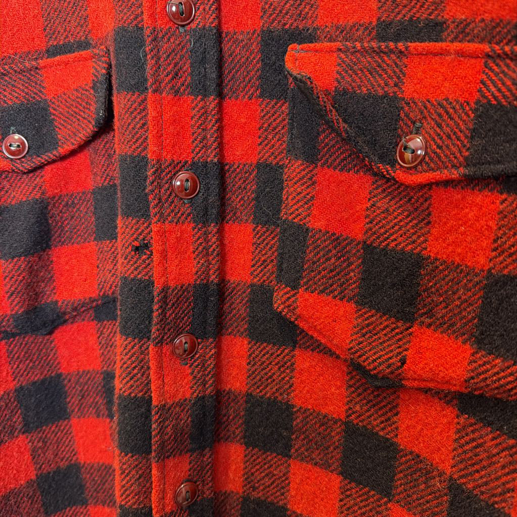 A red plaid long sleeved shirt on a wooden rack. 