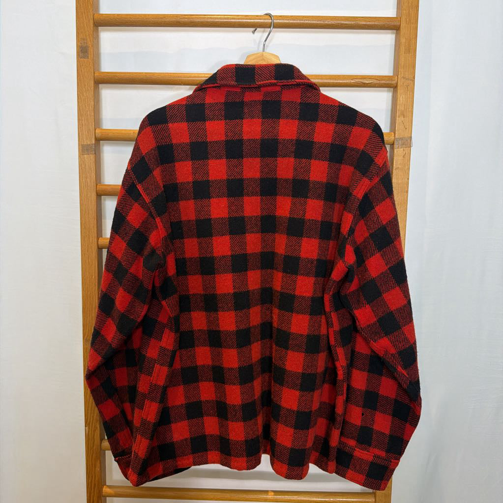 A red plaid long sleeved shirt on a wooden rack. 