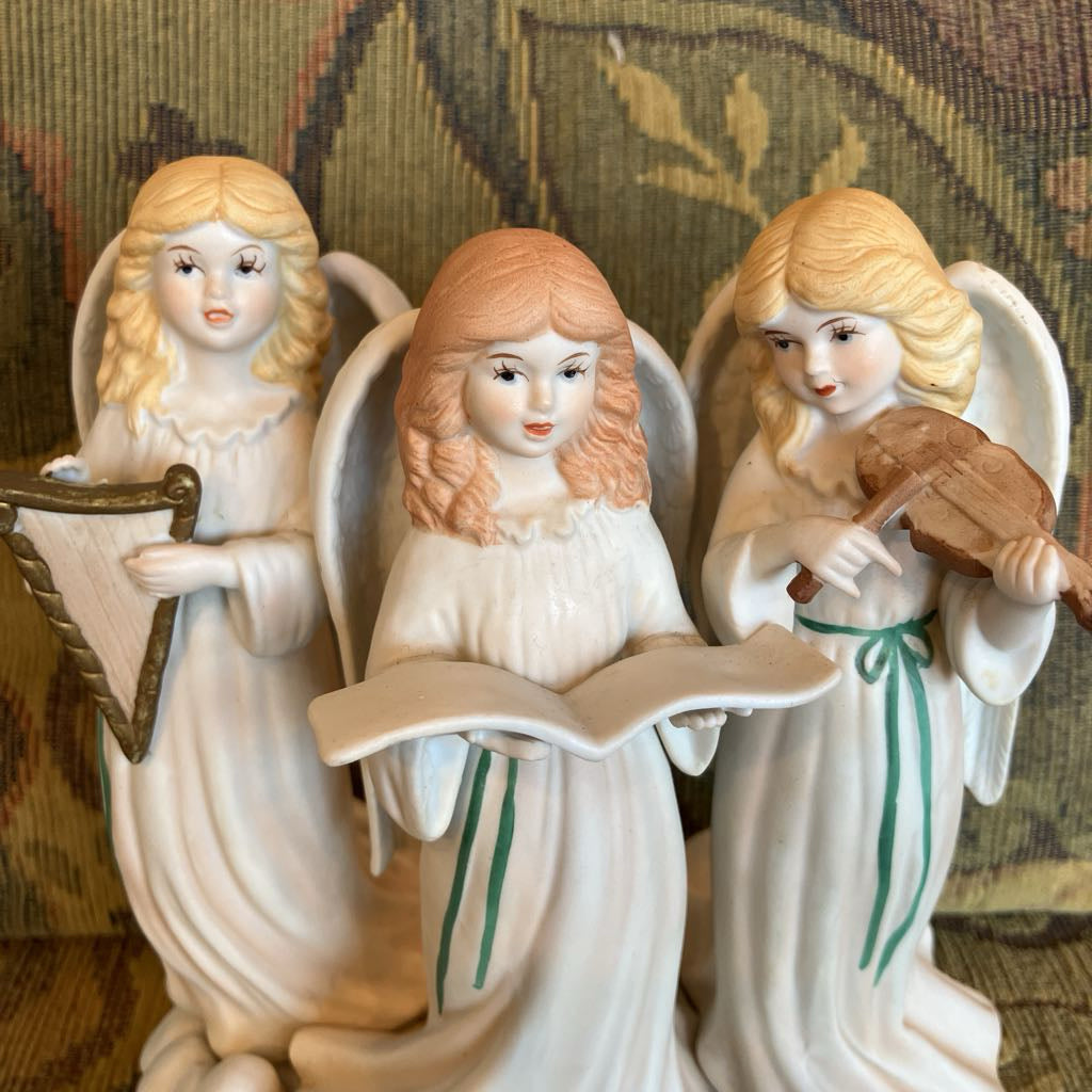 Close up of decorative ceramic figurine of three feminine angels with musical instruments on a cloud base