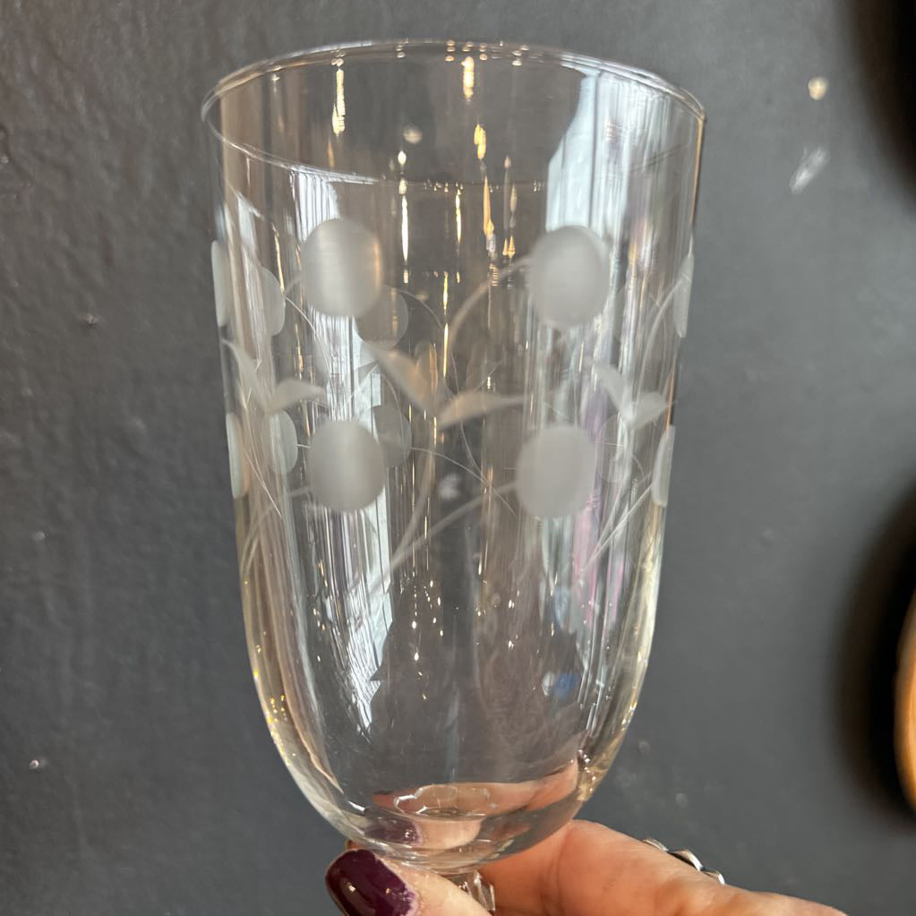 Clear glass with floral etching held against a dark background