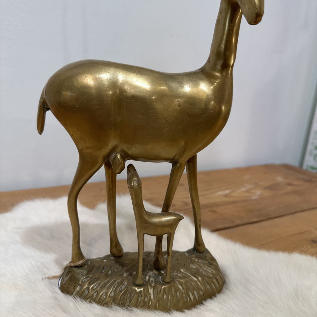 Bronze statue of a deer with a smaller deer figure underneath on a white surface.
