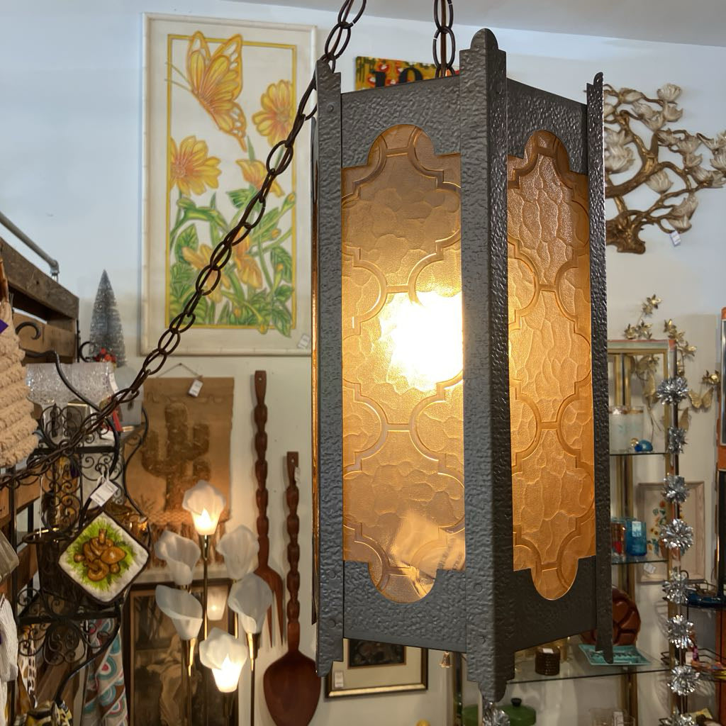 Decorative hanging lamp with intricate design in a room with various items on the wall.