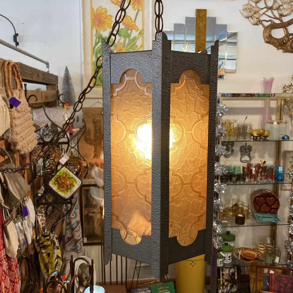 Decorative hanging light fixture in a store with various items in the background