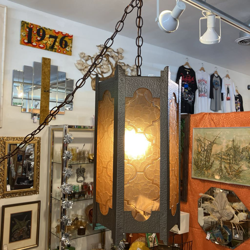 Vintage-style pendant light hanging in a store with mirrors and decor on the walls.