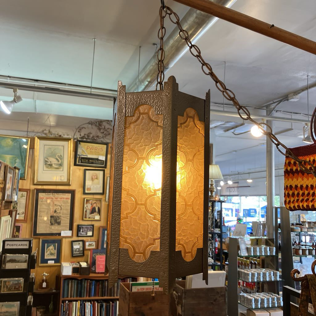 Decorative hanging light fixture in a store with framed pictures on the wall.