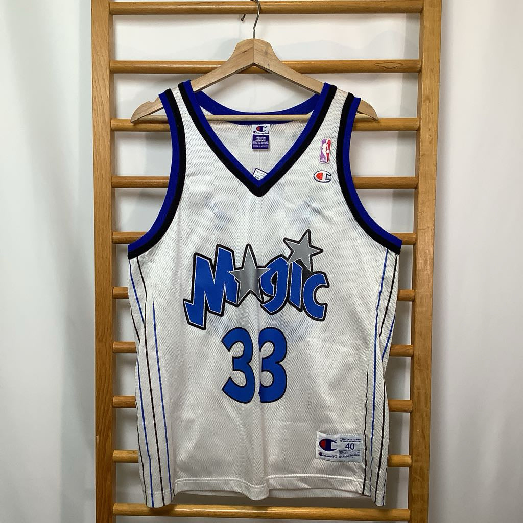 White basketball jersey with blue lettering and number, featuring 'Magic' and '33', on a wooden rack.