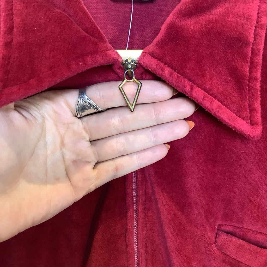Hand wearing a gold ring with a red jacket background