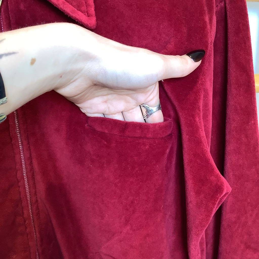 Close-up of a hand with a ring in the pocket of a red jacket.