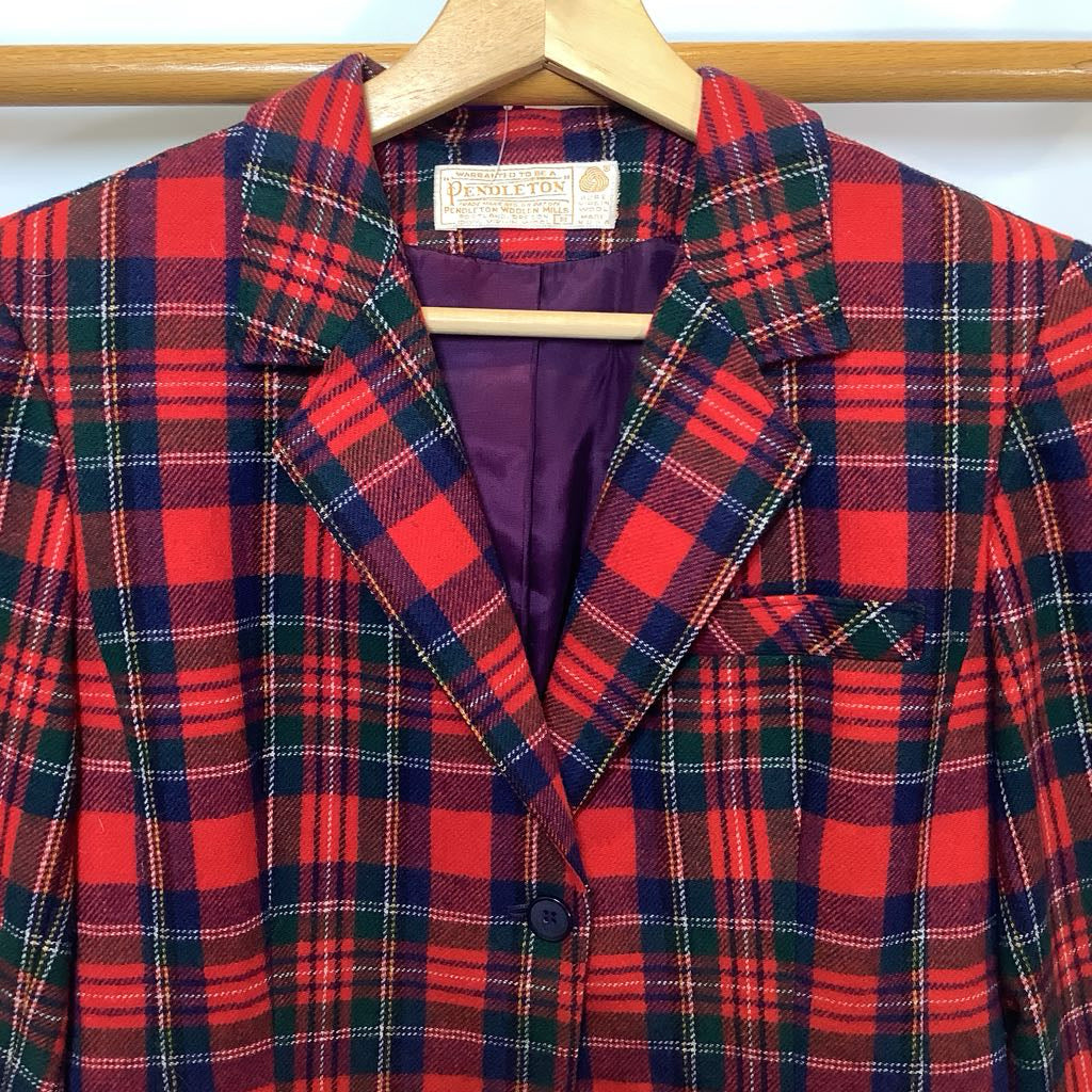 Red and green plaid jacket on a hanger with a visible brand label.