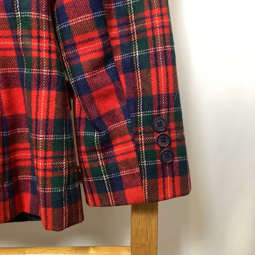 Red and green plaid coat on a wooden stand against a white background