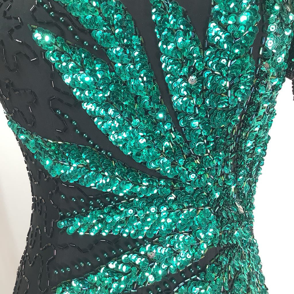 Close-up of a green beaded garment with black accents on a white background
