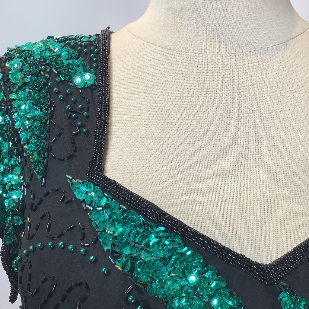 Black dress with green bead embellishments on a mannequin