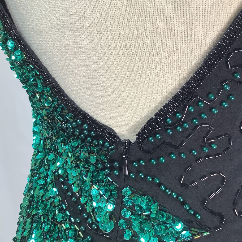 Close-up of a black and green beaded garment on a mannequin.