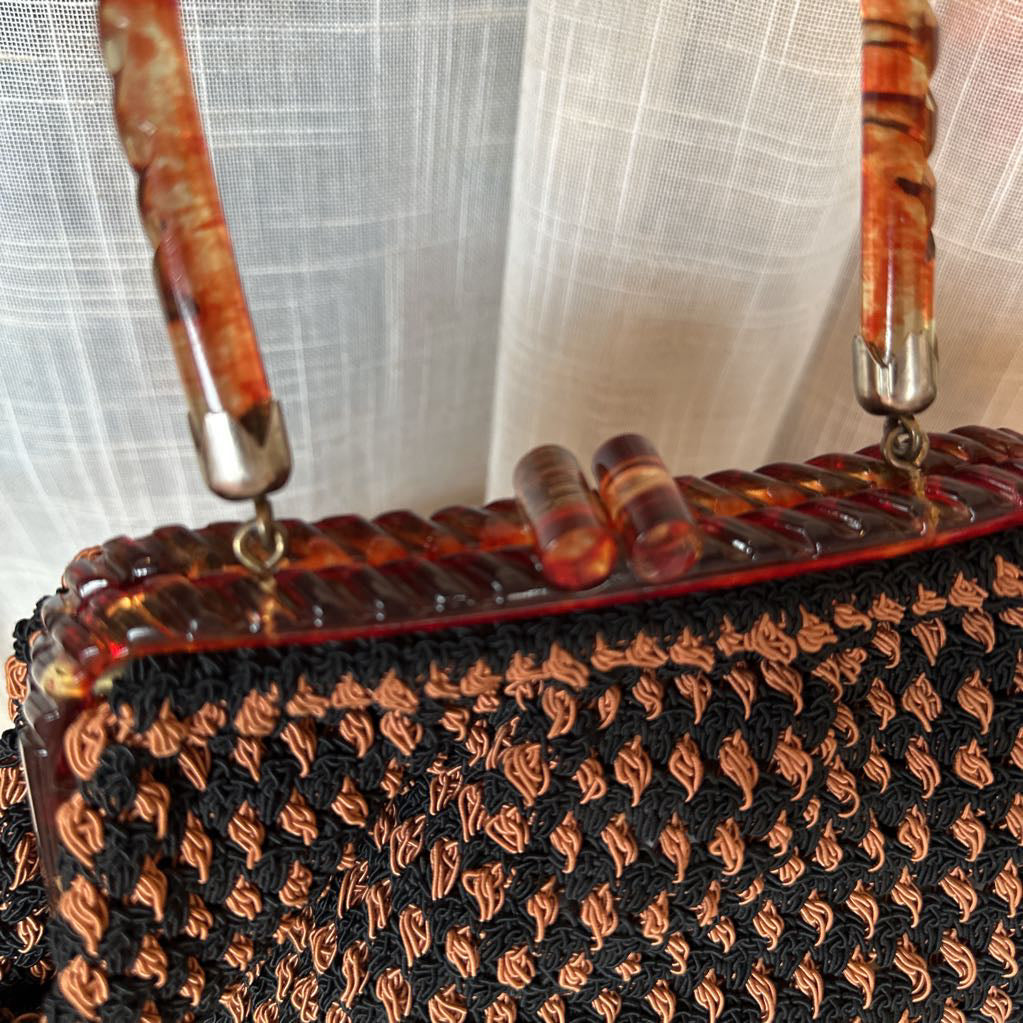 Handbag with tortoiseshell handle against a light fabric background