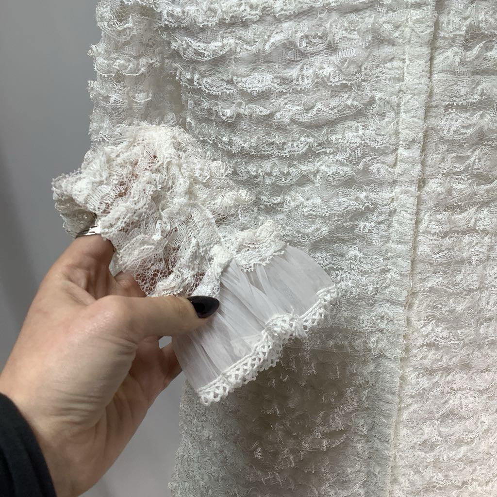 Close-up of a hand holding lace fabric against a textured white background