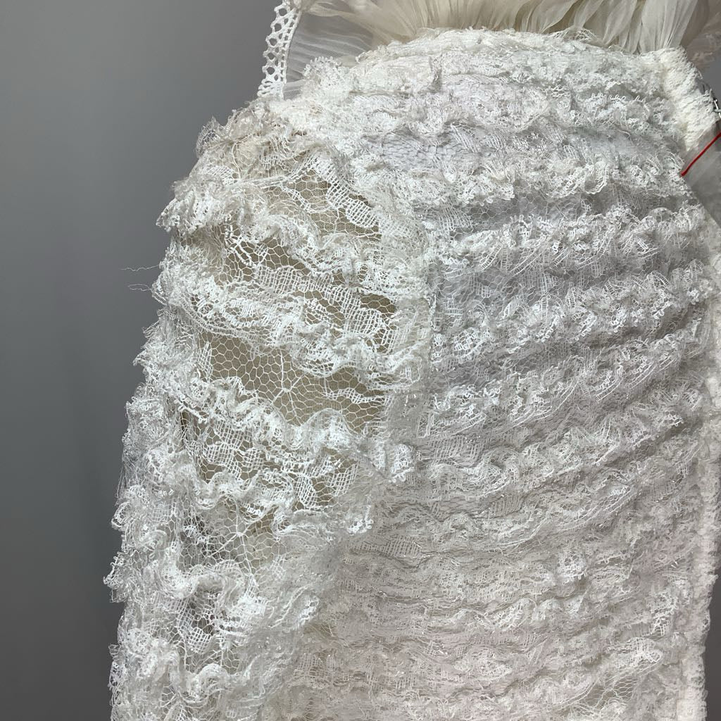 Close-up of a lace wedding dress on a mannequin against a neutral background