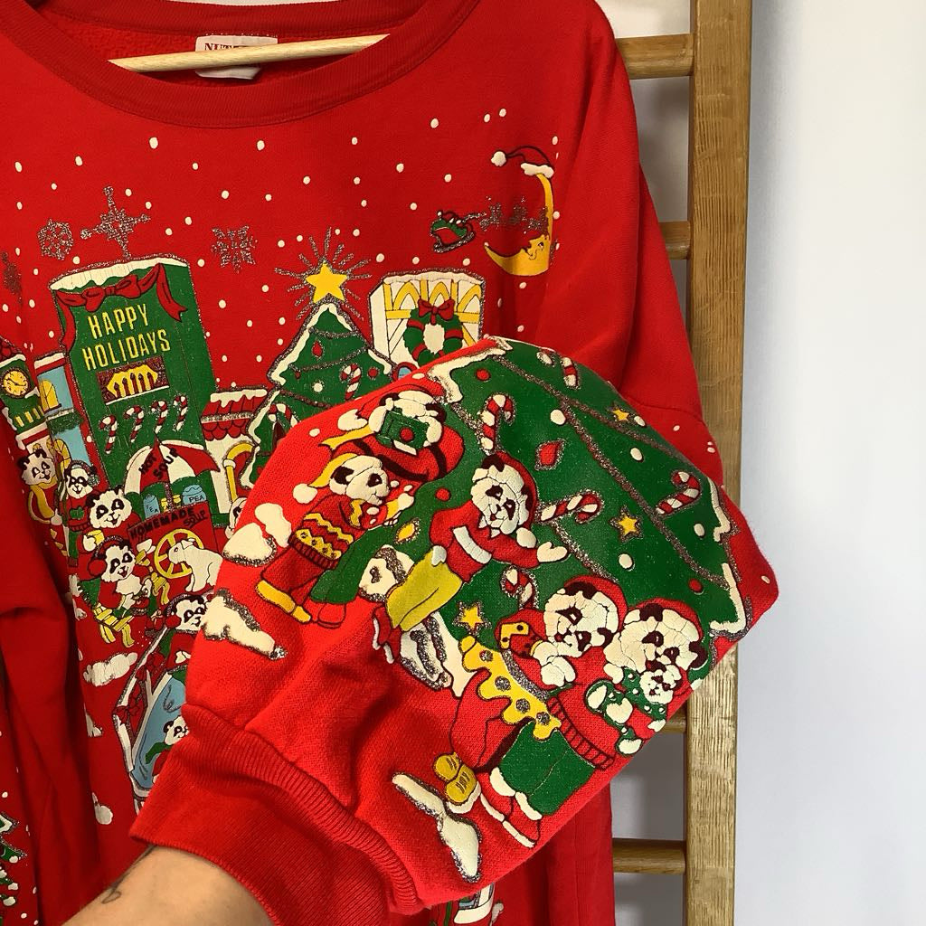 Red Christmas-themed shirt with festive designs on a wooden hanger.
