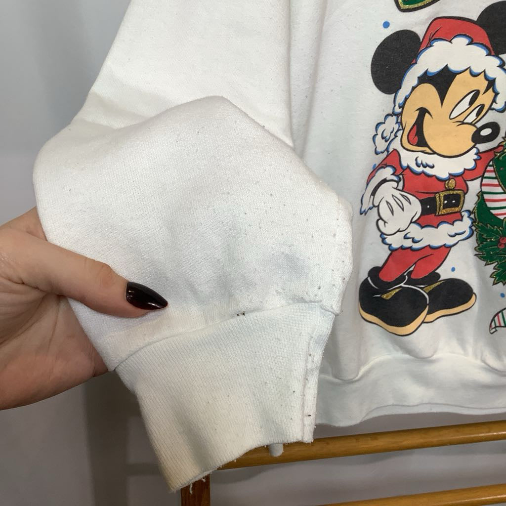 White sweatshirt with a cartoon character design held by a hand.