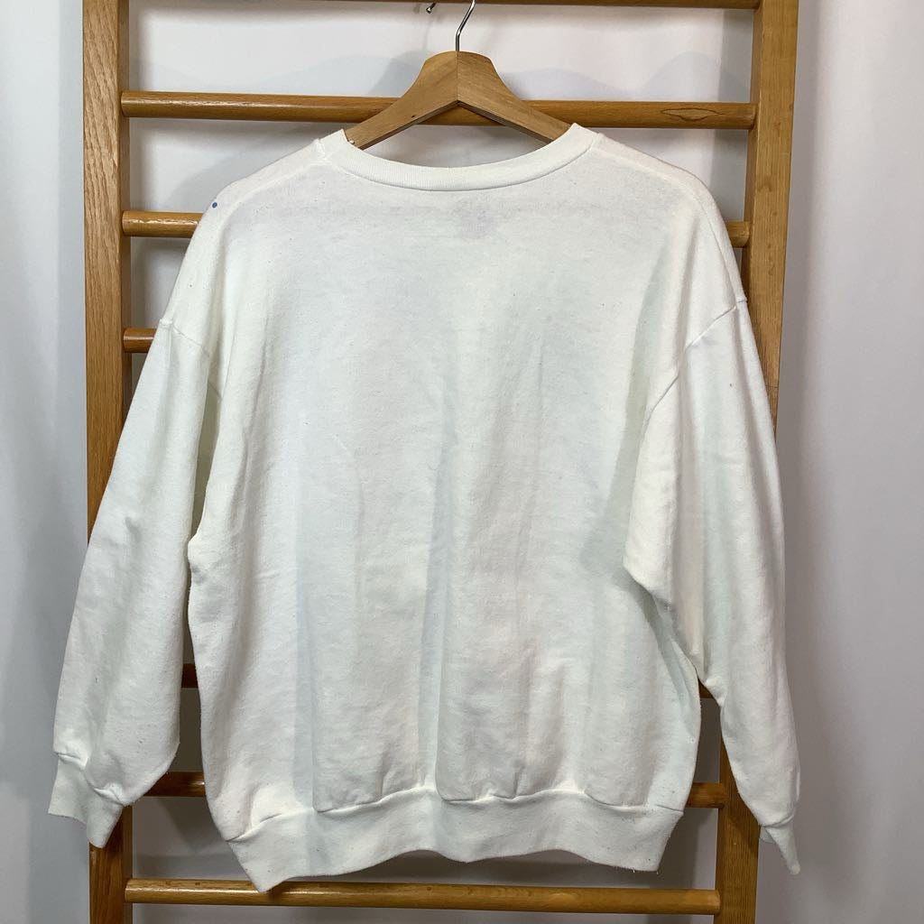White sweatshirt hanging on a wooden rack against a white wall