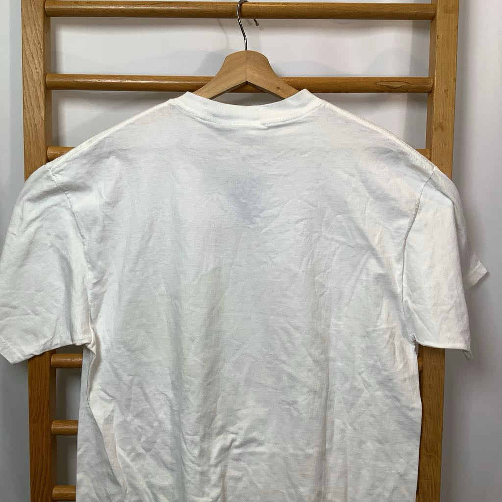 White t-shirt on a wooden hanger against a wooden rack.