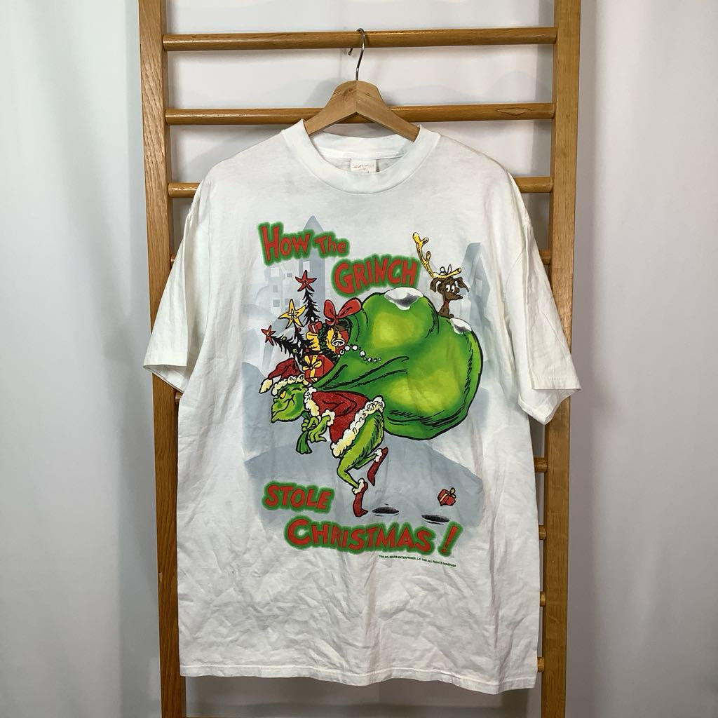 White t-shirt with a green character and text on a wooden rack