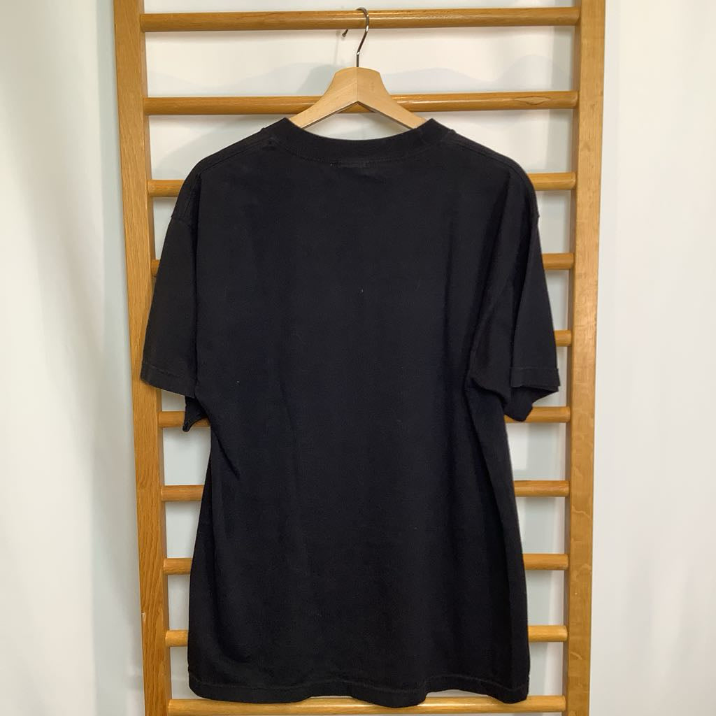 Black t-shirt on a wooden hanger against a white wall