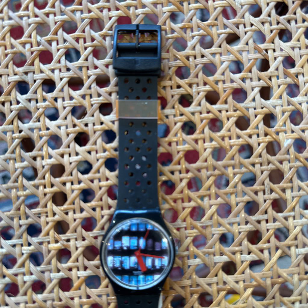 Wristwatch with a black strap on a textured woven surface