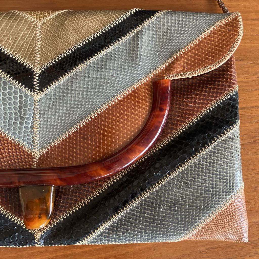 Close up of snakeskin envelope bag on a wooden surface