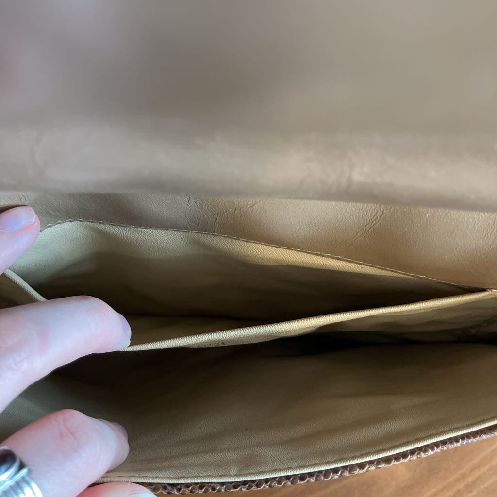 Close-up of a hand holding open a brown leather bag.