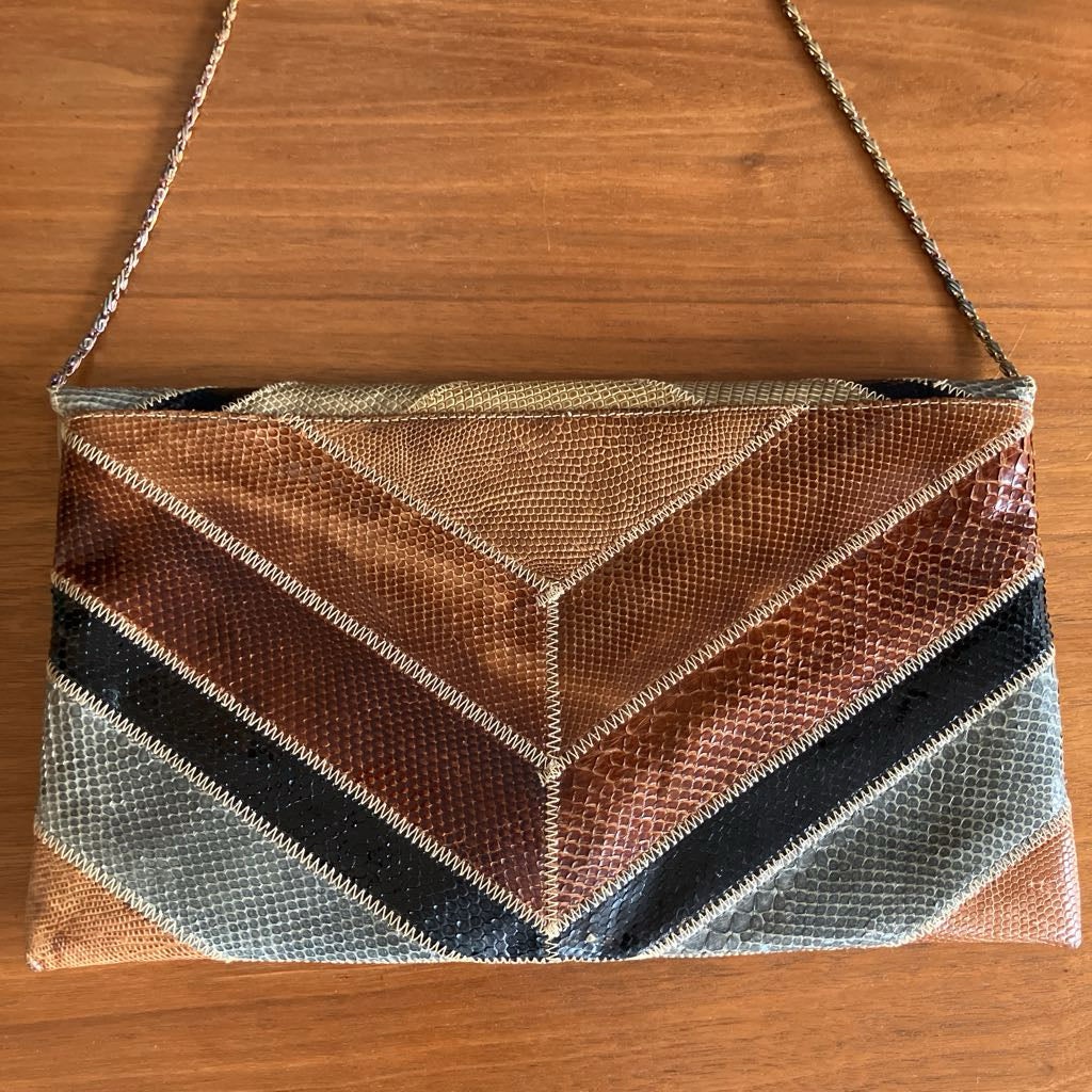 Multi-color snakeskin envelope bag on a wooden surface
