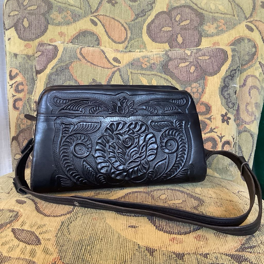 Black leather handbag with floral embossing on a patterned chair