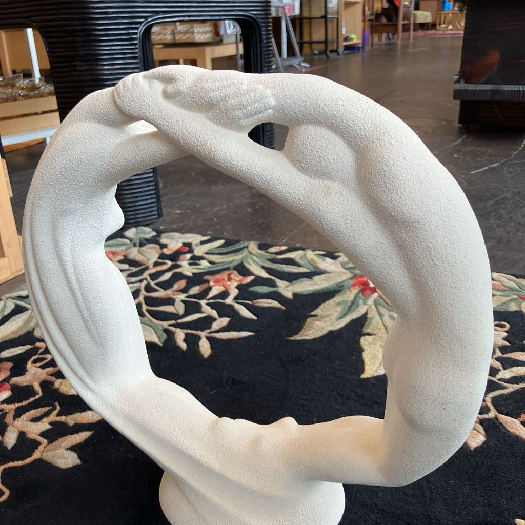 White decorative sculpture with a patterned rug and furniture in the background