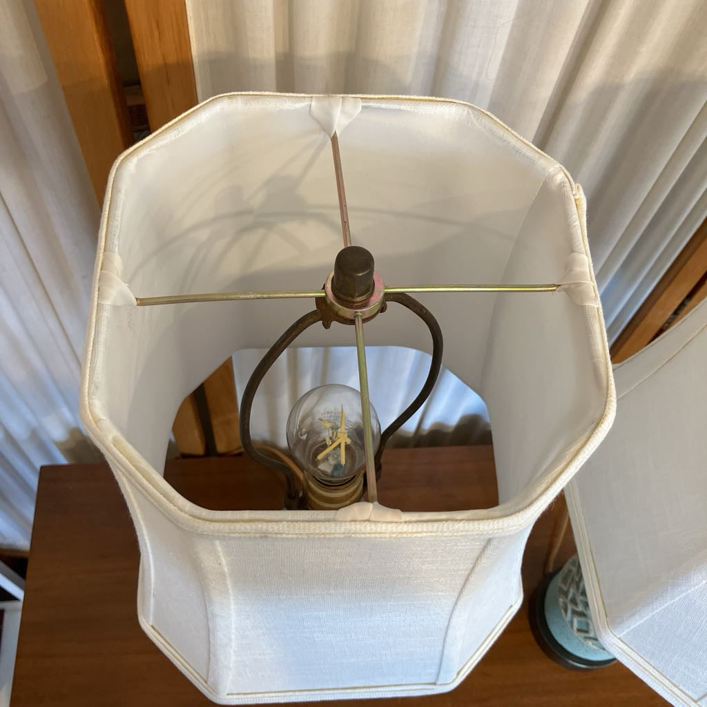 Lampshade with a light bulb inside on a wooden surface.