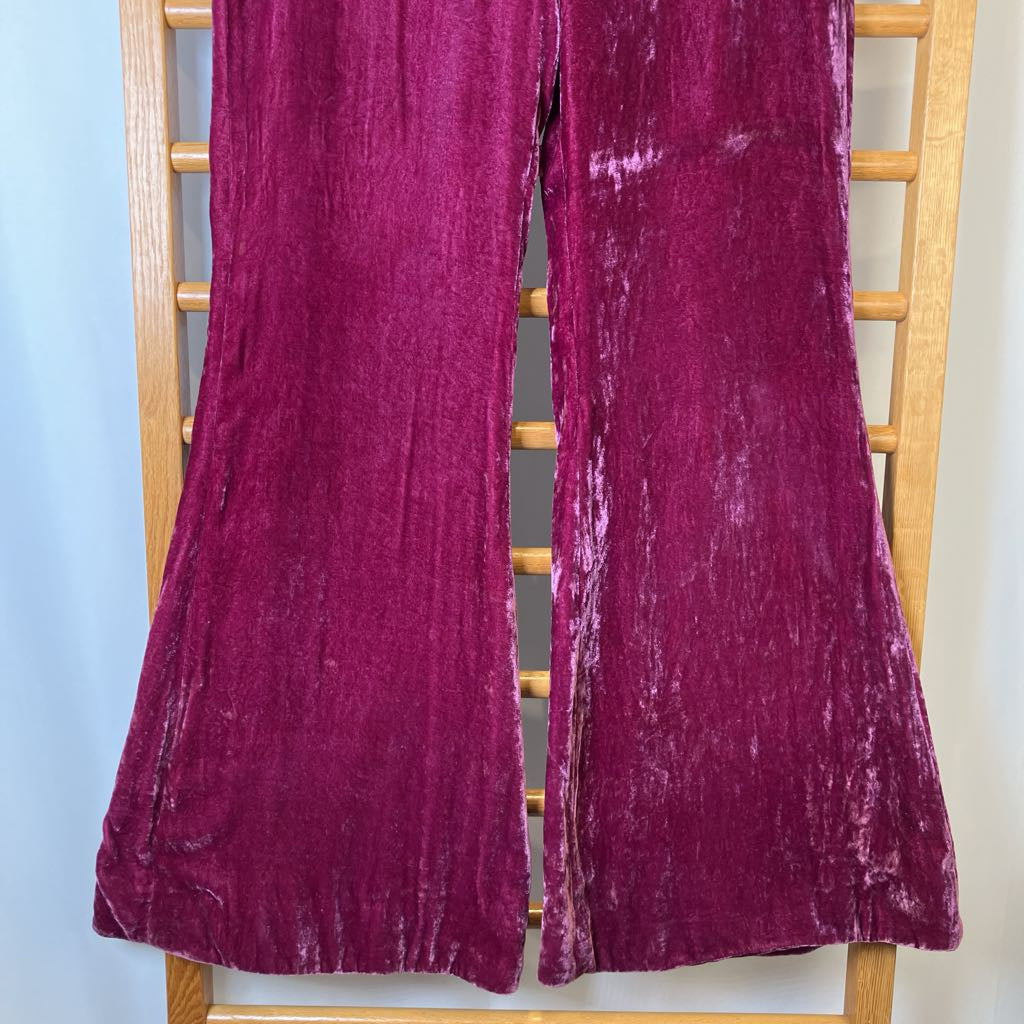 Purple velvet pants on a wooden chair against a light blue wall