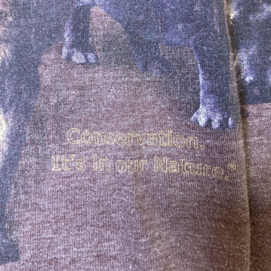 Text 'Conservation: It's in our Nature' on a fabric background with a bear design.