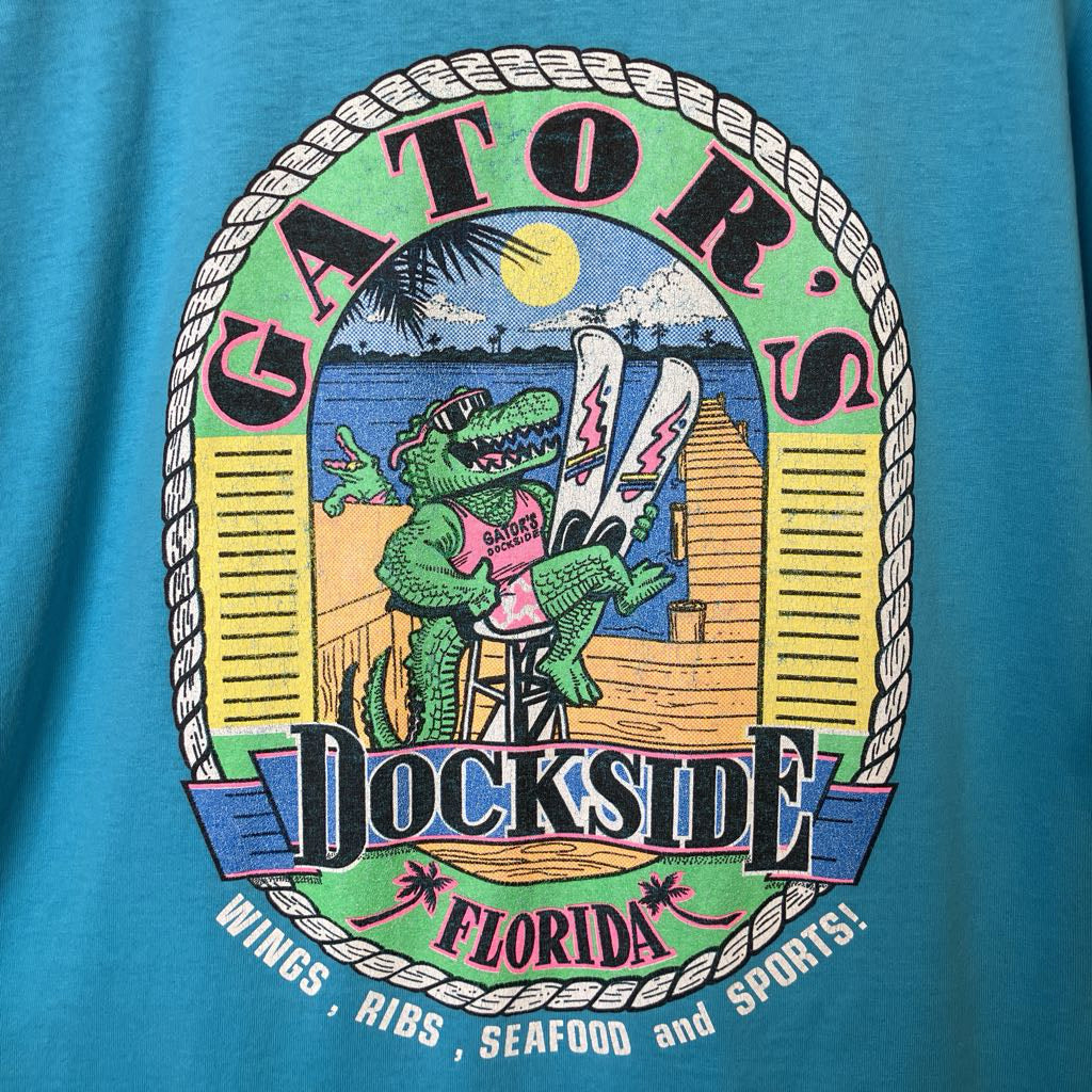 T-shirt with a colorful graphic of a gator at a dockside restaurant in Florida.