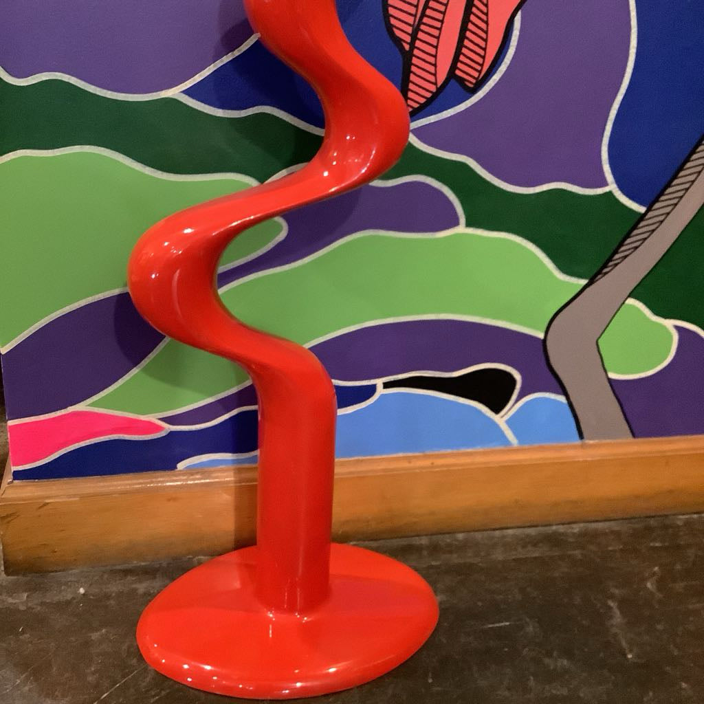 Red wavy sculpture against a colorful abstract wall.