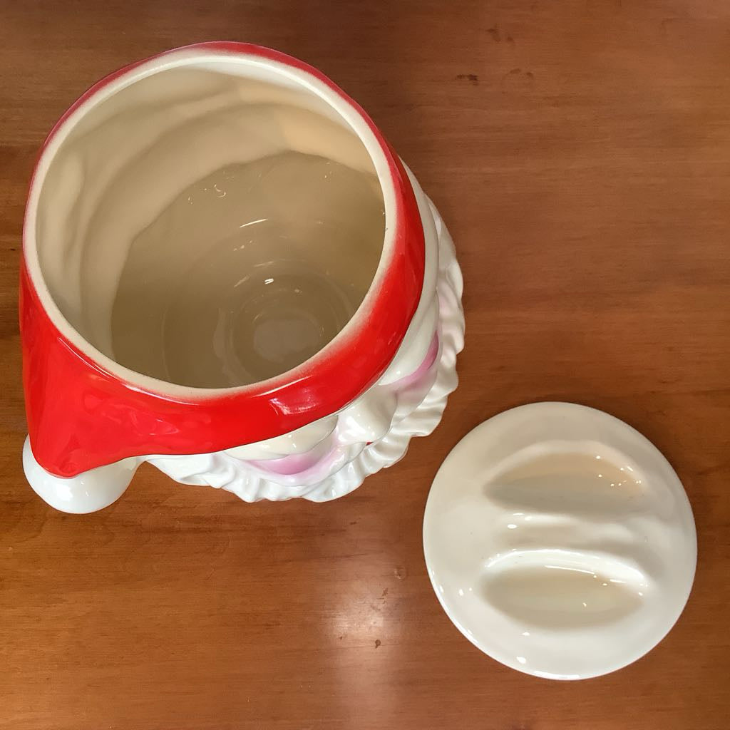 Ceramic container with red rim and white base on a wooden surface