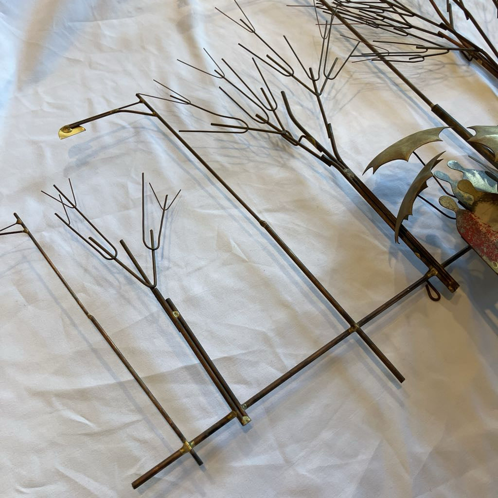 Decorative metal artwork with branches on a white fabric background