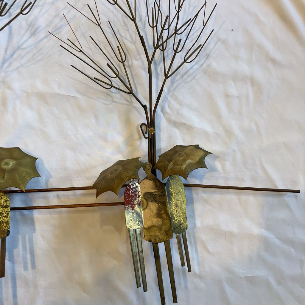 Decorative wall art with metal branches and leaves on a textured white background