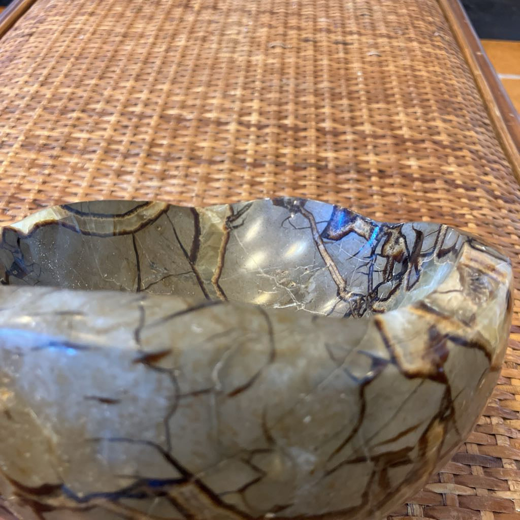 Decorative stone bowl with marbled pattern on a woven surface