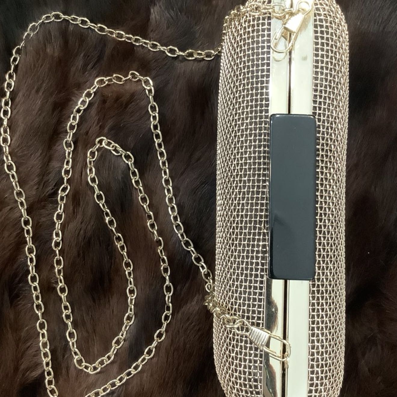 Metallic mesh handbag with chain strap on a dark fur background