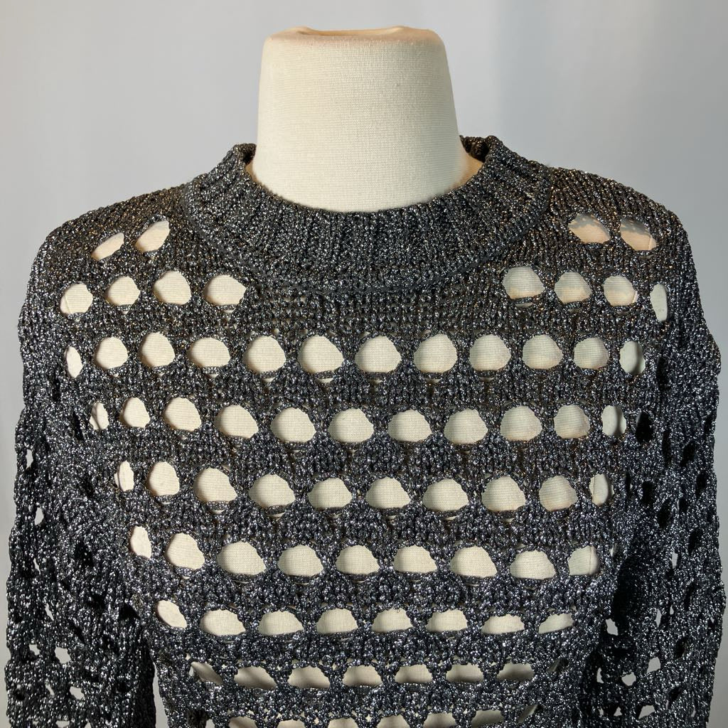 Mannequin wearing a black and white patterned sweater against a gray background