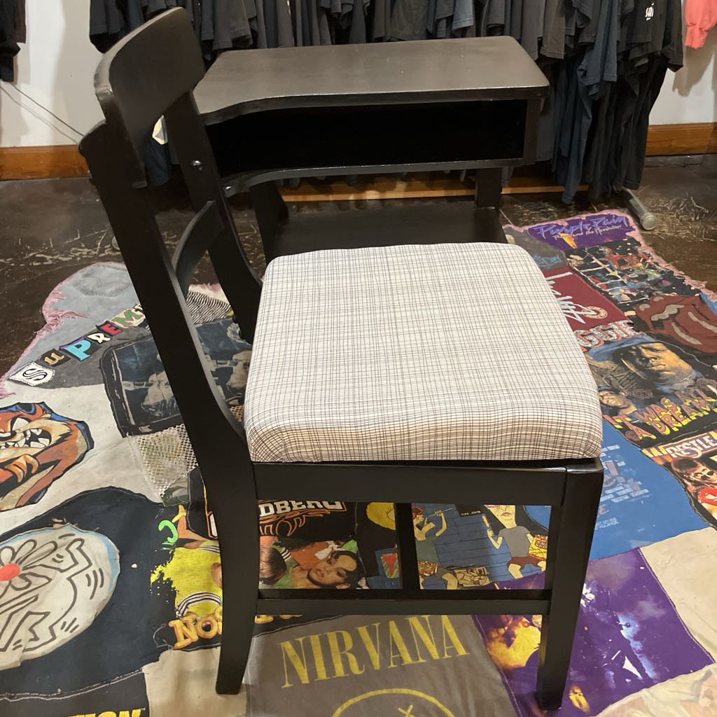 Black chair with a patterned cushion on a colorful rug with graphic designs.